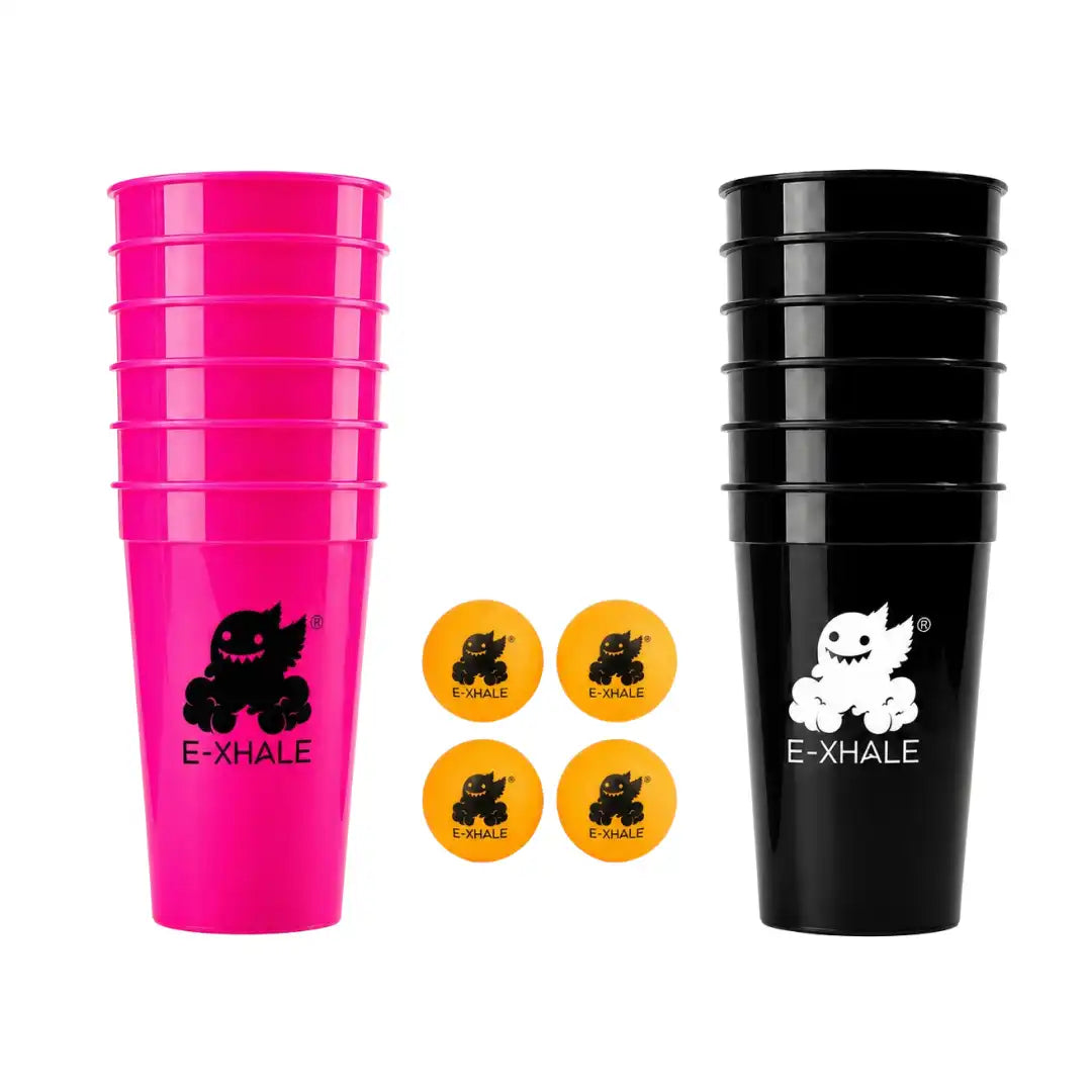 Two stacks of plastic cups on a white background, one bright pink stack with a black E-XHALE logo and text, and one black stack with a white E-XHALE logo and text. Four orange balls with black E-XHALE logos are arranged in the center.
