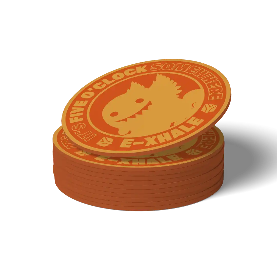 A stack of round orange and yellow coasters featuring a cartoon creature face and the text 'IT'S FIVE O'CLOCK SOMEWHERE' and 'E-XHALE', shown on a white background with a soft shadow.