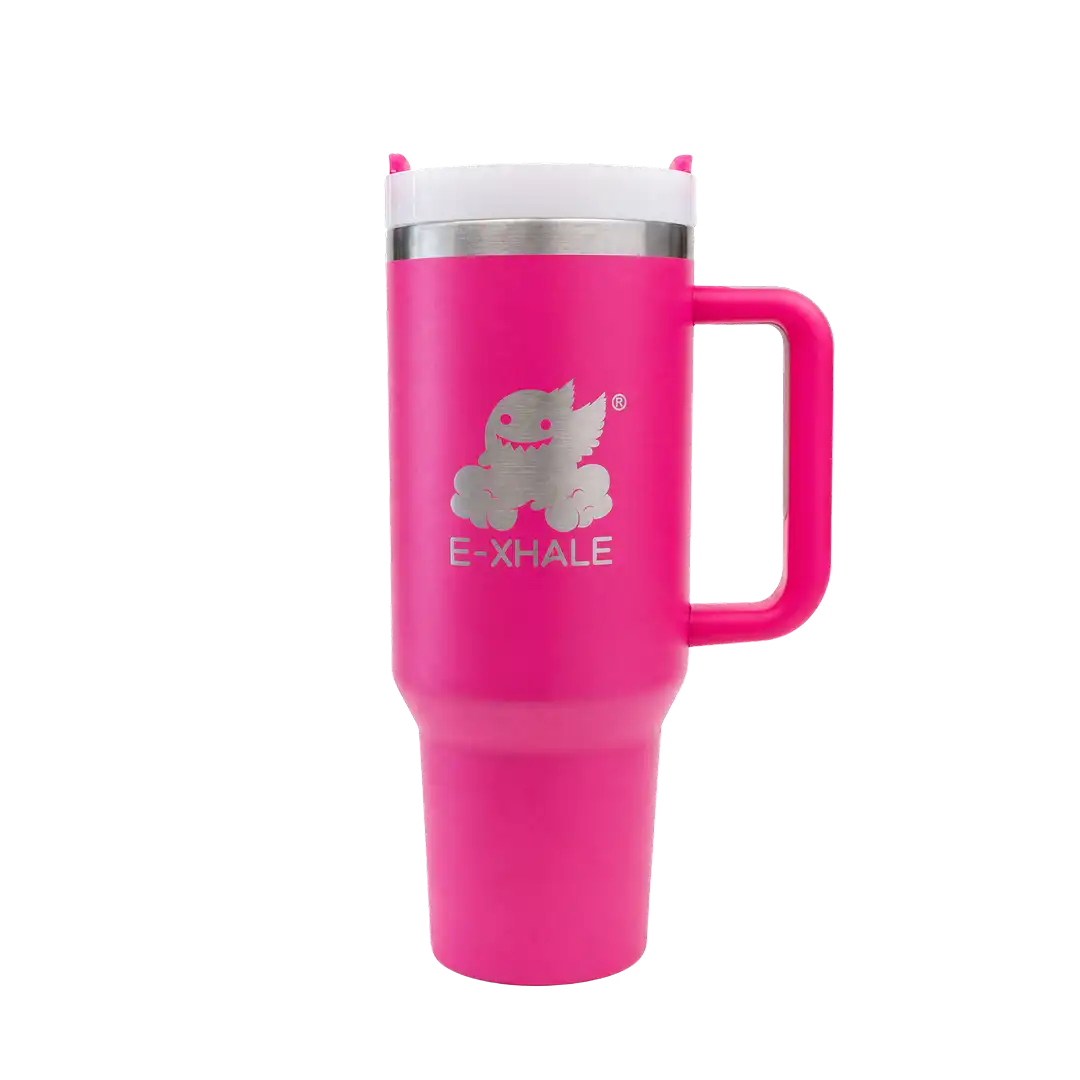 A bright pink insulated travel tumbler with a handle, a white lid, and a silver metallic logo featuring a cartoon creature and the text 'E-XHALE' on the front, set against a plain white background.